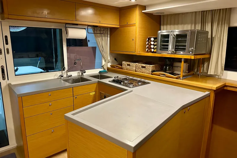 Slide: The Image of Modern kitchen interior on a 2016 Lagoon 450 S yacht, featuring wood cabinetry and appliances. - 75