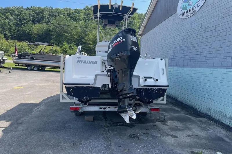 Slide: The Image of 2007 ProKat CS200 boat with Suzuki outboard motor on trailer, parked near marine shop. - 4