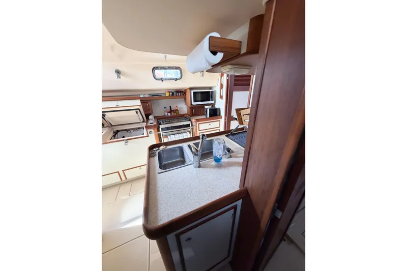 Slide: The Image of 2007 Island Packet SP Cruiser kitchen interior with sink, stove, and wooden cabinetry. - 54