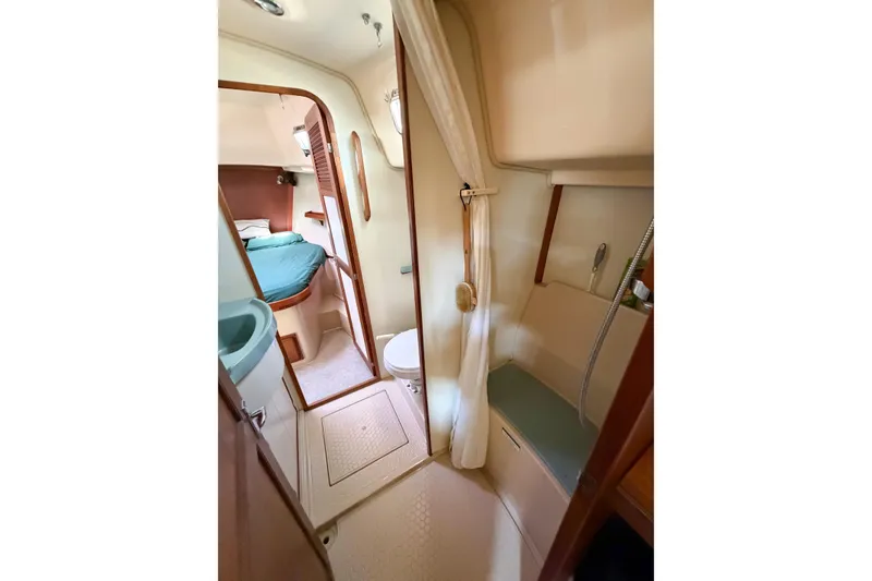 Slide: The Image of Interior of 2007 Island Packet SP Cruiser, featuring a compact bathroom and cozy sleeping area. - 56
