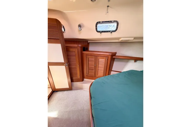 Slide: The Image of Interior cabin of 2007 Island Packet SP Cruiser with wooden cabinets and teal bedding. - 62