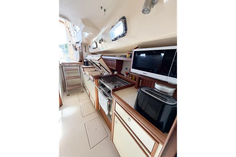 Slide: The Image of 2007 Island Packet SP Cruiser galley with stove, microwave, and toaster in a compact layout. - 63