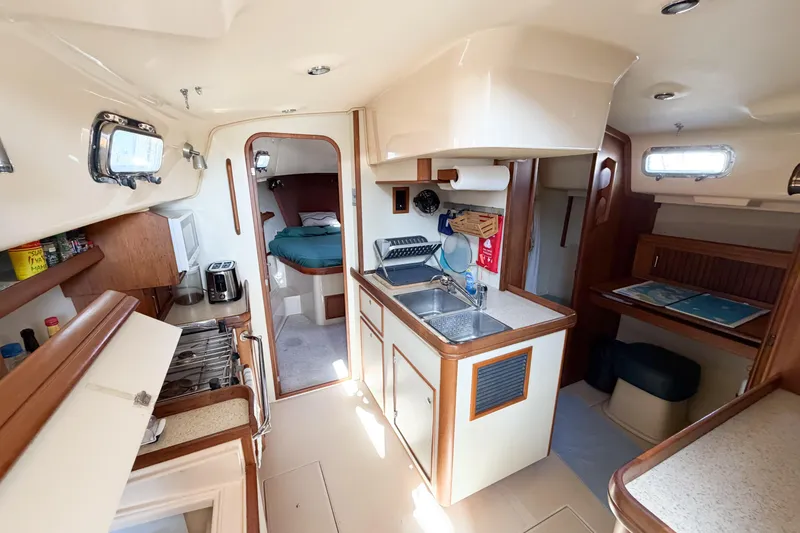 Slide: The Image of Interior of 2007 Island Packet SP Cruiser yacht, featuring kitchen and cozy sleeping area. - 67