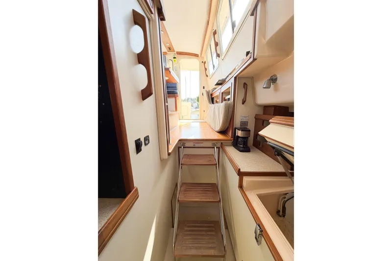 Slide: The Image of Interior view of 2007 Island Packet SP Cruiser, featuring compact kitchen and wooden steps. - 68