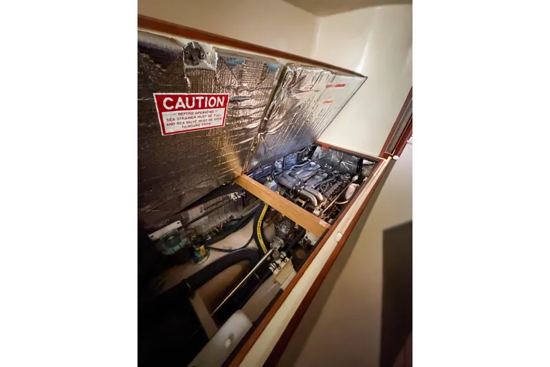 Slide: The Image of Engine compartment of 2007 Island Packet SP Cruiser with caution sign visible. - 77
