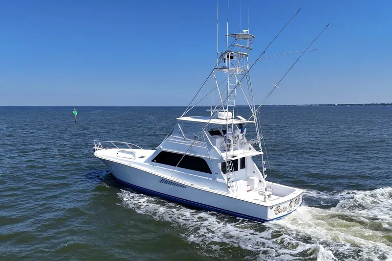 Slide: The Image of 1997 Viking 58 Convertible yacht cruising on open water under clear blue skies. - 10