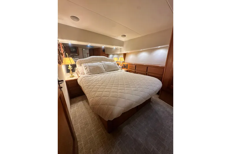Slide: The Image of Luxurious bedroom interior of 1997 Viking 58 Convertible yacht with cozy bedding and ambient lighting. - 102