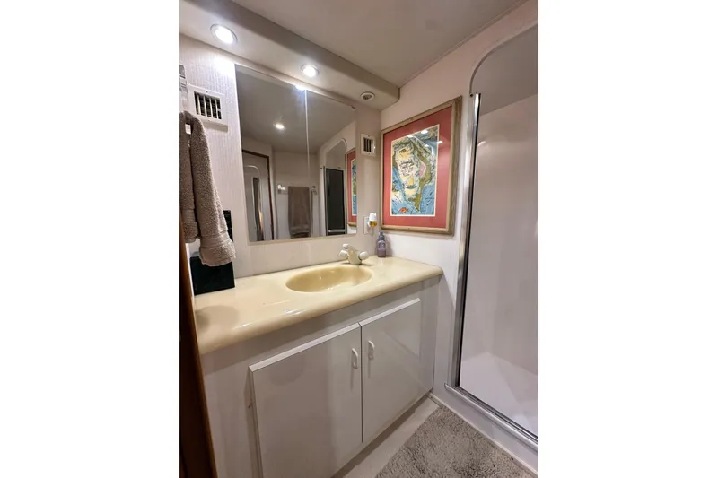 Slide: The Image of Bathroom interior of 1997 Viking 58 Convertible yacht with sink, mirror, and framed artwork. - 114