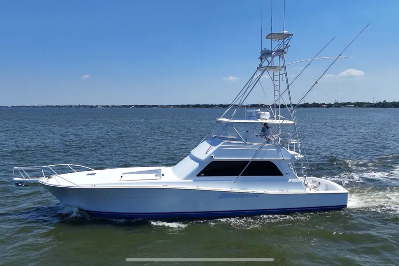 Slide: The Image of 1997 Viking 58 Convertible yacht cruising on open water under clear blue skies. - 12