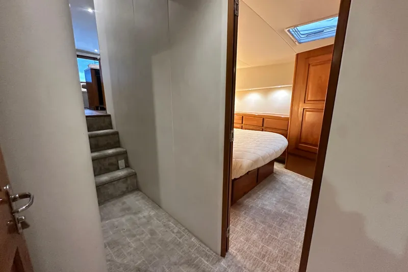 Slide: The Image of Interior of 1997 Viking 58 Convertible yacht, featuring a cozy bedroom and carpeted stairs. - 130