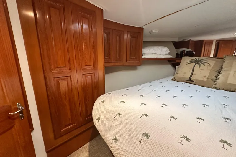 Slide: The Image of Bedroom interior of 1997 Viking 58 Convertible yacht with wooden cabinetry and palm-themed bedding. - 135