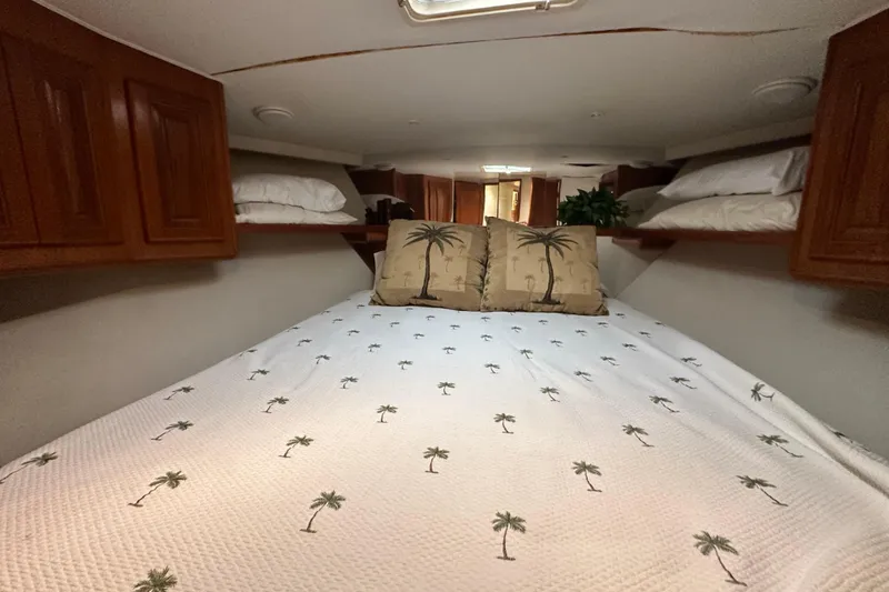 Slide: The Image of Cozy bedroom in 1997 Viking 58 Convertible yacht with palm-themed bedding and wooden cabinets. - 137