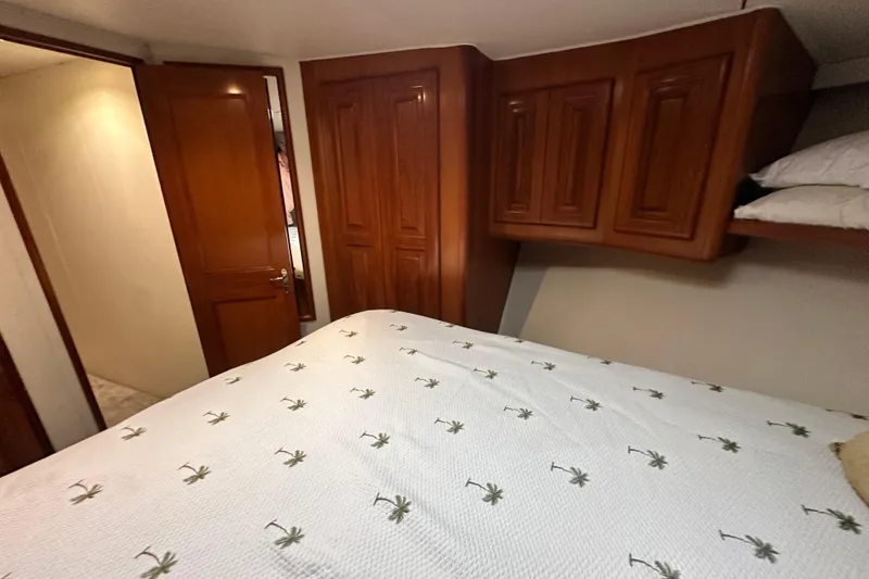 Slide: The Image of Cozy bedroom in 1997 Viking 58 Convertible yacht with wooden cabinets and palm-patterned bedding. - 138