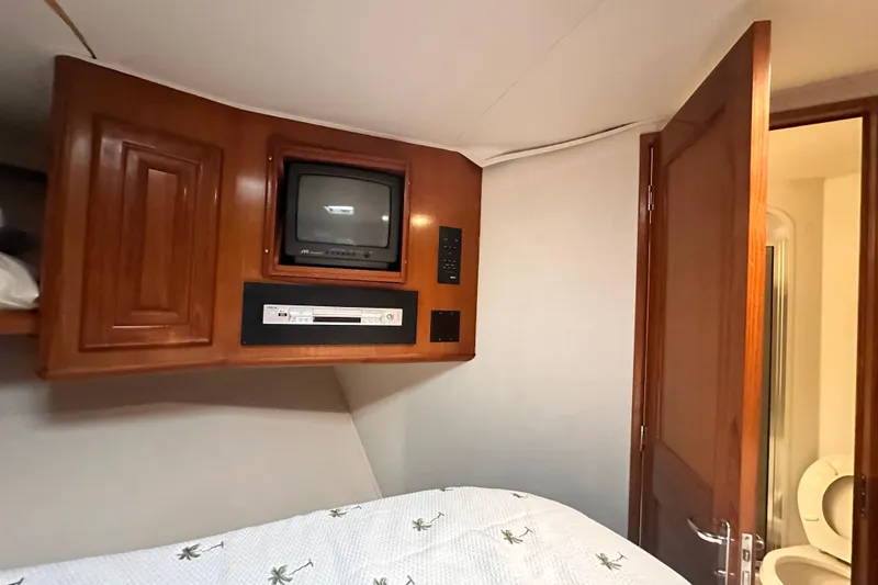 Slide: The Image of 1997 Viking 58 Convertible cabin with vintage TV, DVD player, and wooden cabinetry. - 140