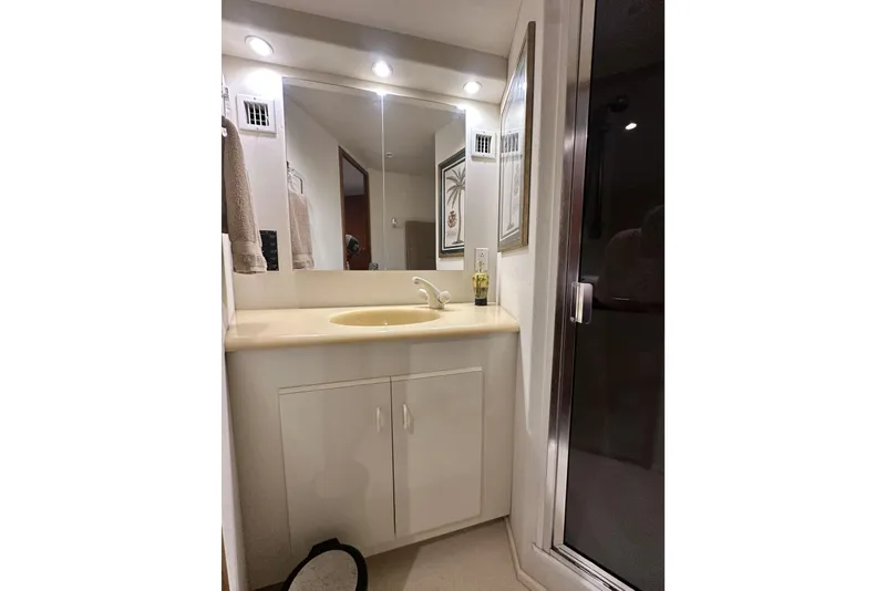 Slide: The Image of Bathroom vanity in 1997 Viking 58 Convertible yacht, featuring a sink, mirror, and lighting. - 146