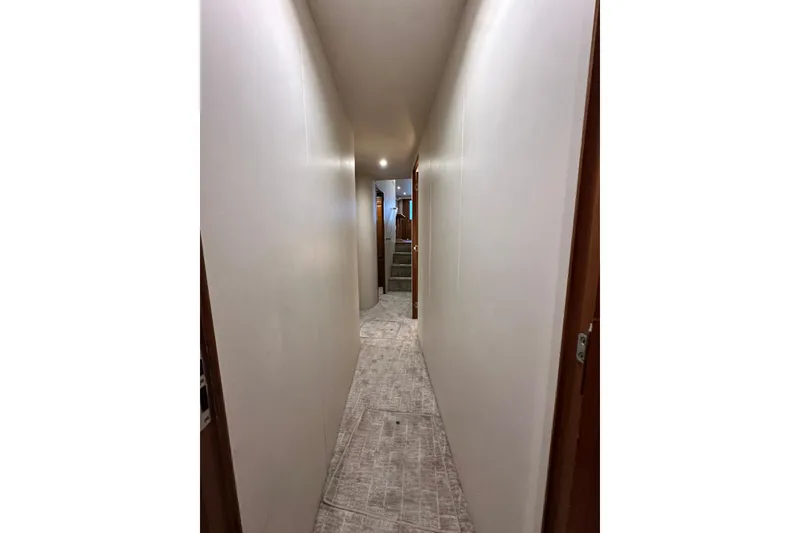 Slide: The Image of Narrow hallway inside a 1997 Viking 58 Convertible yacht, featuring carpeted flooring and wooden doors. - 148