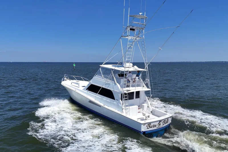 Slide: The Image of 1997 Viking 58 Convertible yacht cruising on open water under clear blue skies. - 2