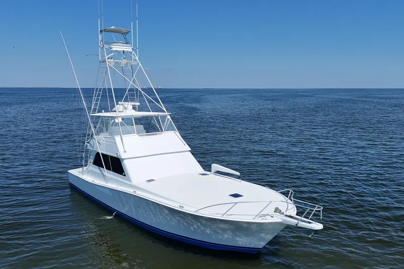Slide: The Image of 1997 Viking 58 Convertible yacht on calm ocean waters under clear blue sky. - 22