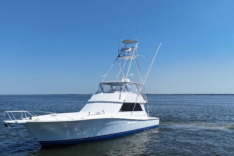 Slide: The Image of 1997 Viking 58 Convertible yacht cruising on open water under clear blue sky. - 23