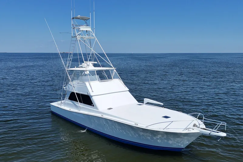Slide: The Image of 1997 Viking 58 Convertible yacht on calm ocean waters under clear blue sky. - 24