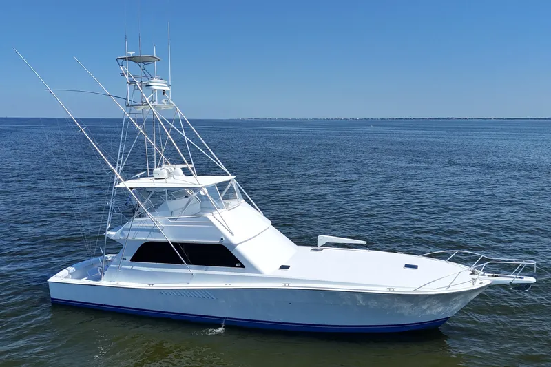 Slide: The Image of 1997 Viking 58 Convertible yacht on calm ocean waters under clear blue sky. - 25