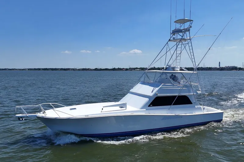 Slide: The Image of 1997 Viking 58 Convertible yacht cruising on open water under clear blue skies. - 26