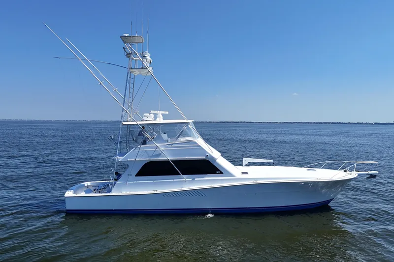 Slide: The Image of 1997 Viking 58 Convertible yacht on calm blue waters under clear sky. - 27