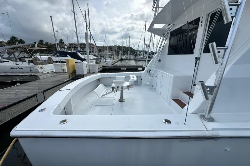 Slide: The Image of 1997 Viking 58 Convertible yacht docked at marina, showcasing spacious deck and fishing equipment. - 32