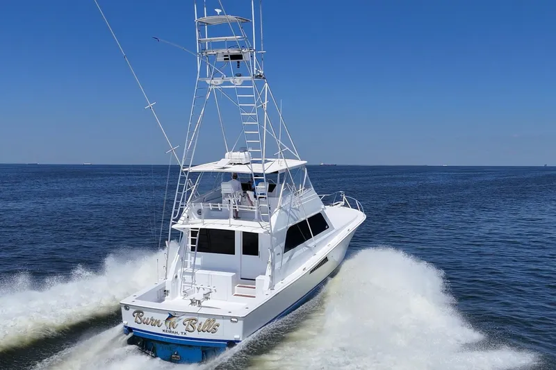 Slide: The Image of 1997 Viking 58 Convertible yacht cruising on open water under clear blue skies. - 4