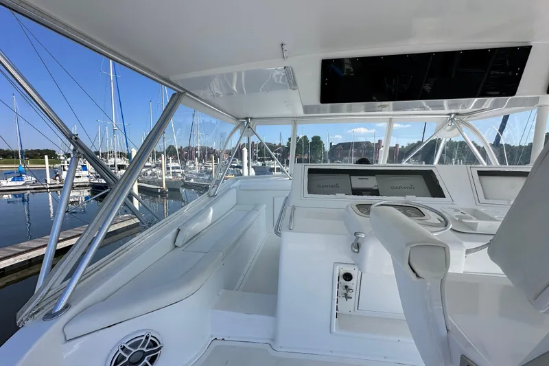 Slide: The Image of 1997 Viking 58 Convertible yacht helm with marina view, featuring Garmin navigation systems. - 42