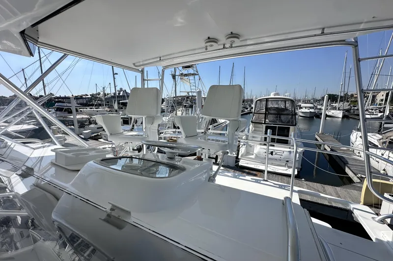 Slide: The Image of Flybridge of 1997 Viking 58 Convertible yacht at marina, featuring helm chairs and clear skies. - 49
