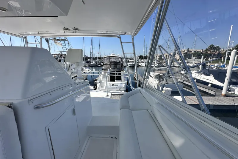 Slide: The Image of 1997 Viking 58 Convertible yacht interior with marina view, featuring white seating and helm station. - 52
