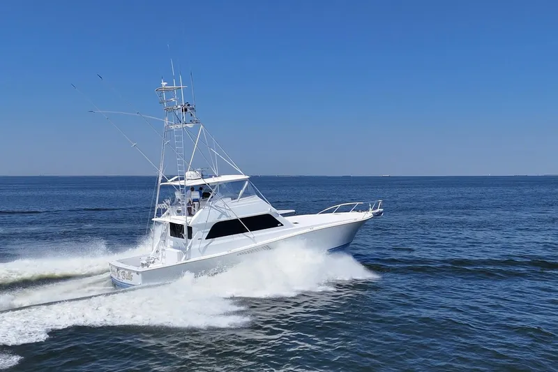 Slide: The Image of 1997 Viking 58 Convertible yacht cruising on open water under clear blue sky. - 8
