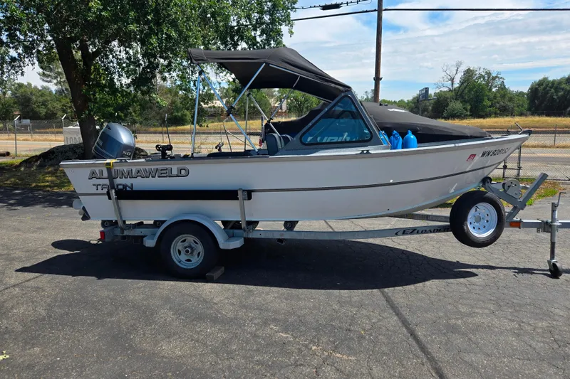 The Image of 2016 Alumaweld Talon 16 boat on trailer, parked outdoors under a tree. - 1