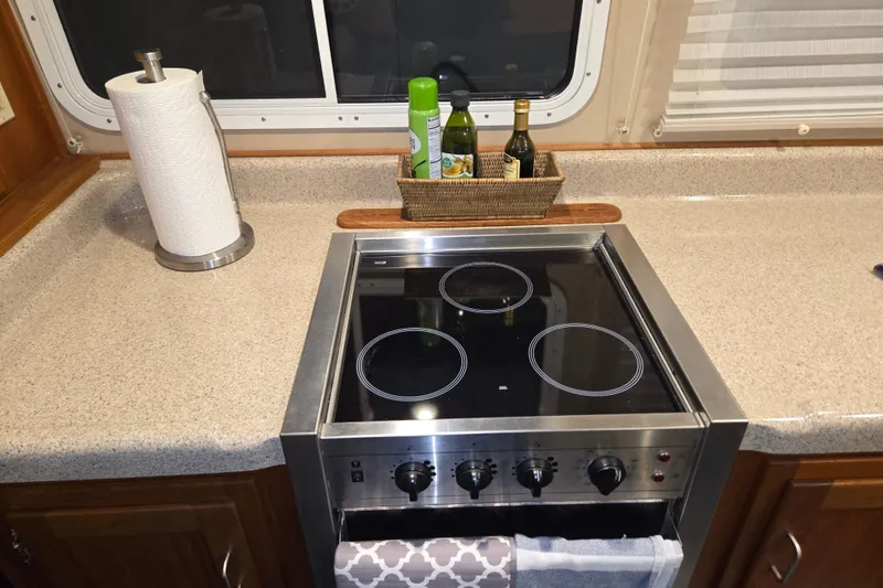 Slide: The Image of Galley kitchen in 2006 American Tug 34 Pilothouse Trawler with electric stove and countertop essentials. - 25