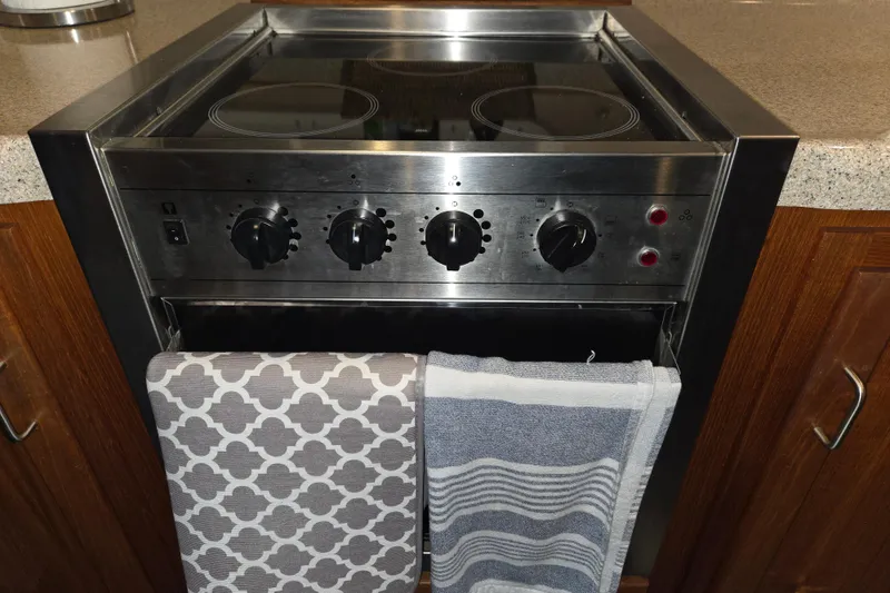 Slide: The Image of Stainless steel stove with control knobs, featuring patterned and striped towels hanging. - 26