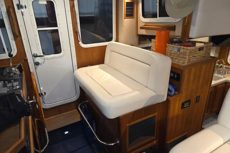 Slide: The Image of Interior of 2006 American Tug 34 Pilothouse Trawler with white seating and wooden accents. - 32