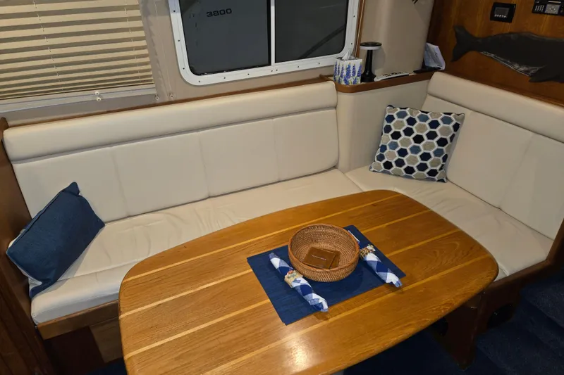 Slide: The Image of Cozy dining area in 2006 American Tug 34 Pilothouse Trawler with wooden table and cushions. - 4