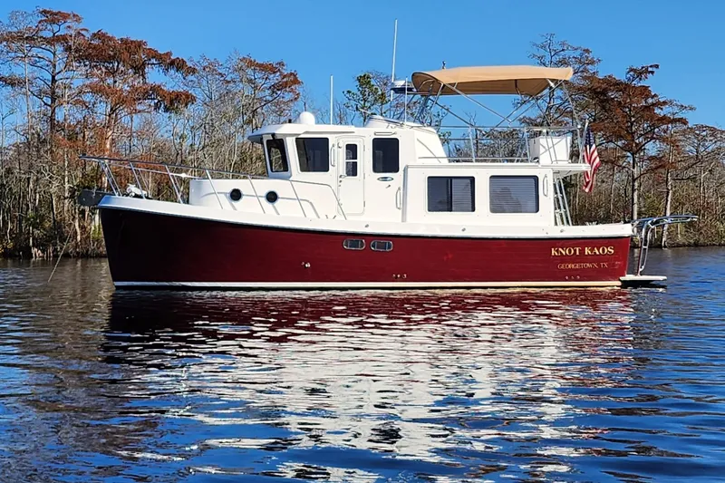 Slide: The Image of 2006 American Tug 34 Pilothouse Trawler on serene water, surrounded by trees. - 60