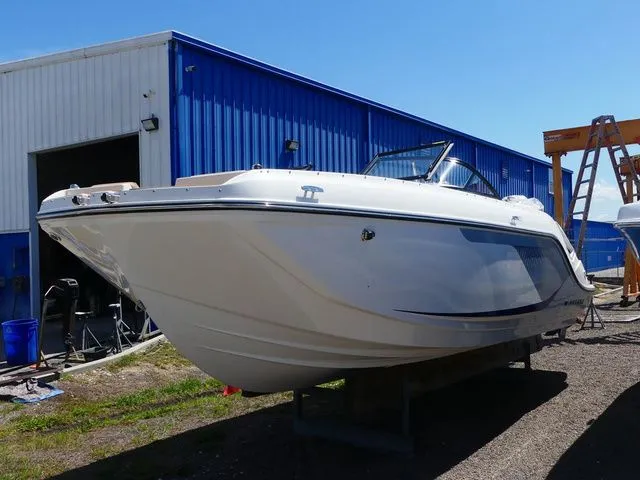 The Image of Bayliner D22 2026 boat parked outside blue warehouse. - 1
