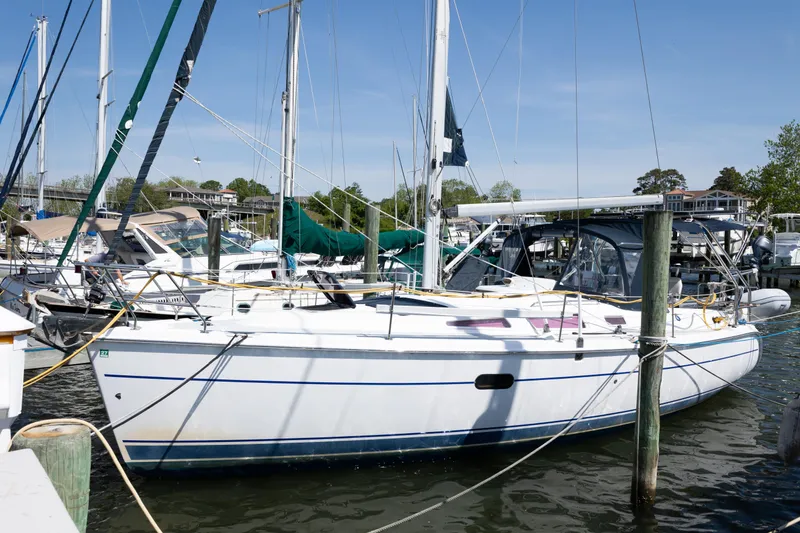 The Image of 2005 Hunter 36 sailboat docked at marina, surrounded by other boats under clear blue sky. - 0