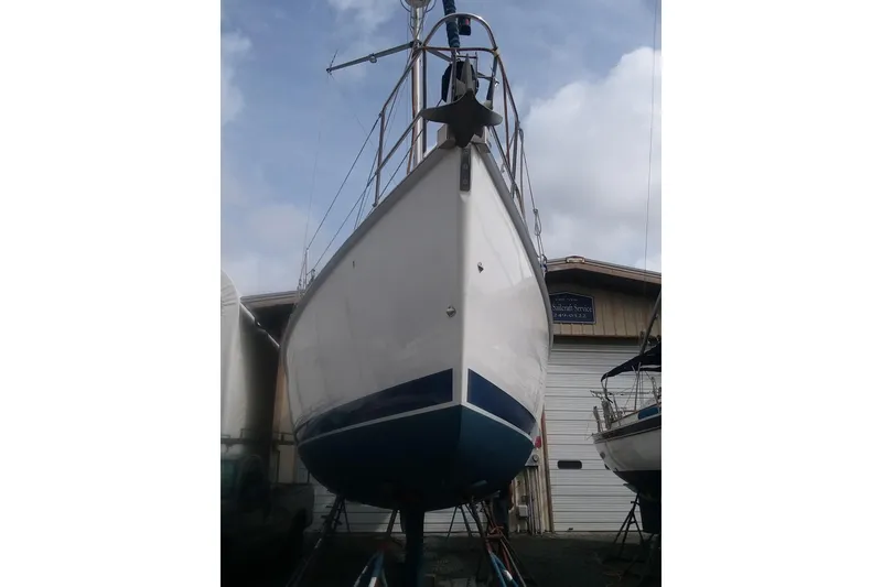 Slide: The Image of 2005 Hunter 36 sailboat on stands, viewed from the bow, with a cloudy sky background. - 82