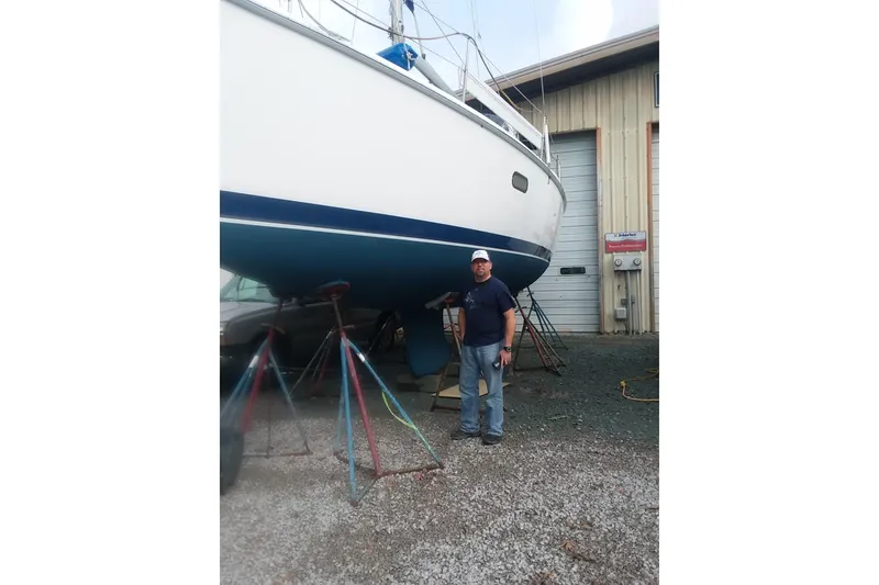 Slide: The Image of Man standing beside a 2005 Hunter 36 sailboat in a boatyard. - 83