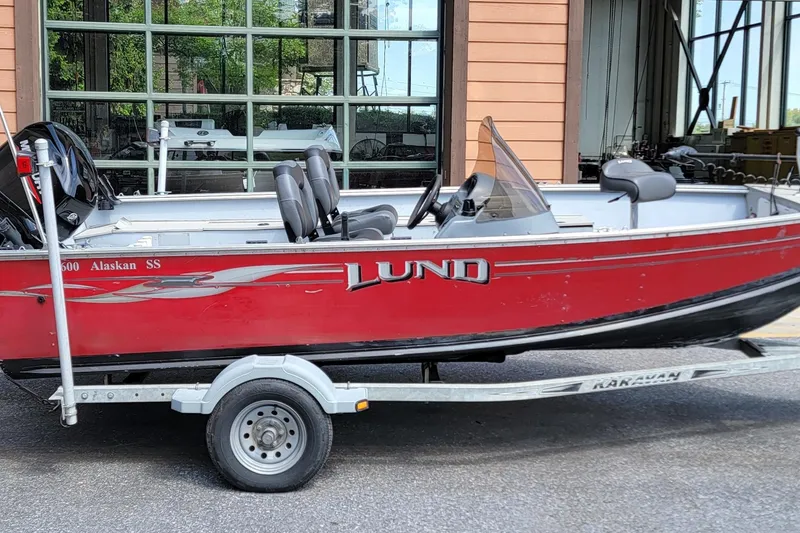 The Image of Red 2006 Lund 2000 Alaskan SS boat on trailer, parked outside a building. - 0