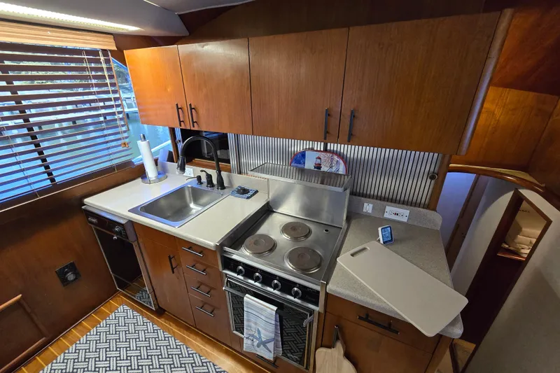Slide: The Image of 1993 Ocean Yachts 53 Super Sport kitchen with wooden cabinets, stove, and sink. - 13