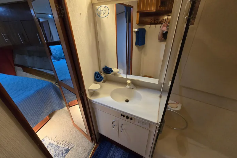 Slide: The Image of 1993 Ocean Yachts 53 Super Sport bathroom with sink, mirror, and adjacent bedroom view. - 18