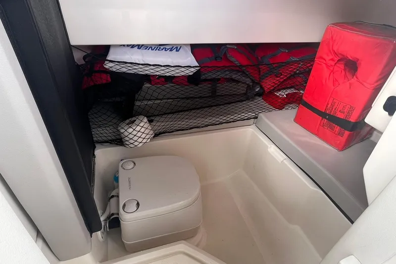 Slide: The Image of 2021 Sea Ray SDX 250 Outboard interior with portable toilet and safety equipment storage. - 26