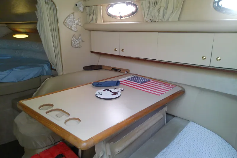 Slide: The Image of Interior of 1998 Sea Ray Sundancer 330 with table, American flag, and cozy seating. - 23
