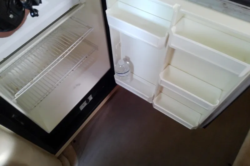 Slide: The Image of Open refrigerator inside a 1998 Sea Ray Sundancer 330 boat, showing empty shelves and a water bottle. - 34