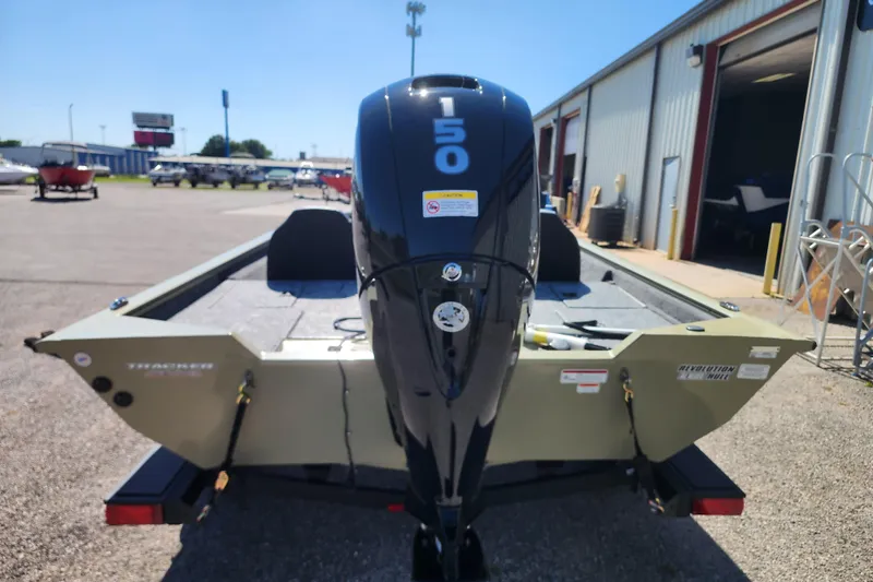Slide: The Image of 2026 Tracker Pro Team 195 boat with 150 HP engine, parked outside a warehouse. - 5